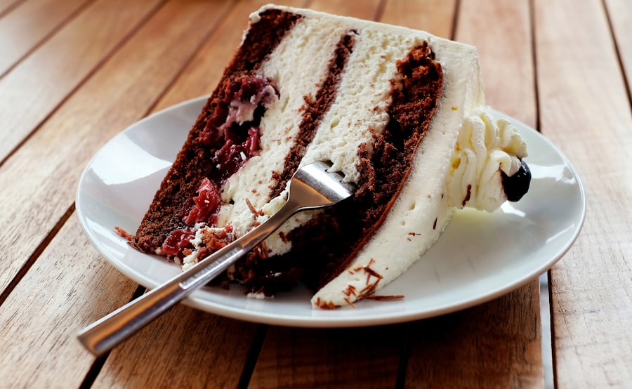 Slice of layered chocolate cake with cream and cherries on a plate